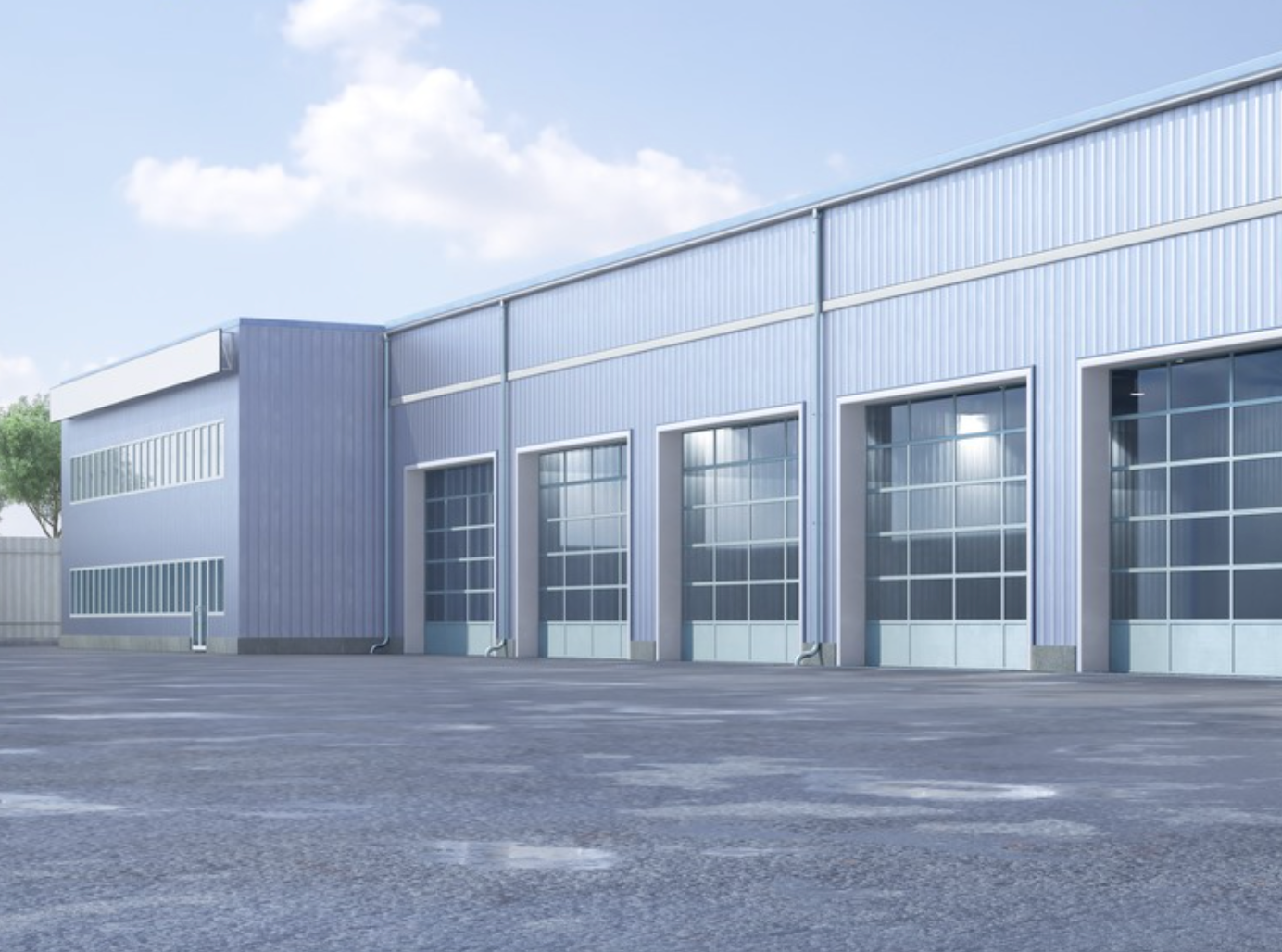 Large gray industrial warehouse with garage doors under a bright sky