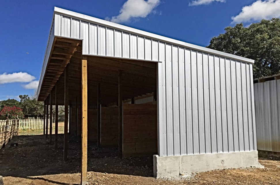 Partially constructed white shed with open front and exposed wooden framing under a blue sky