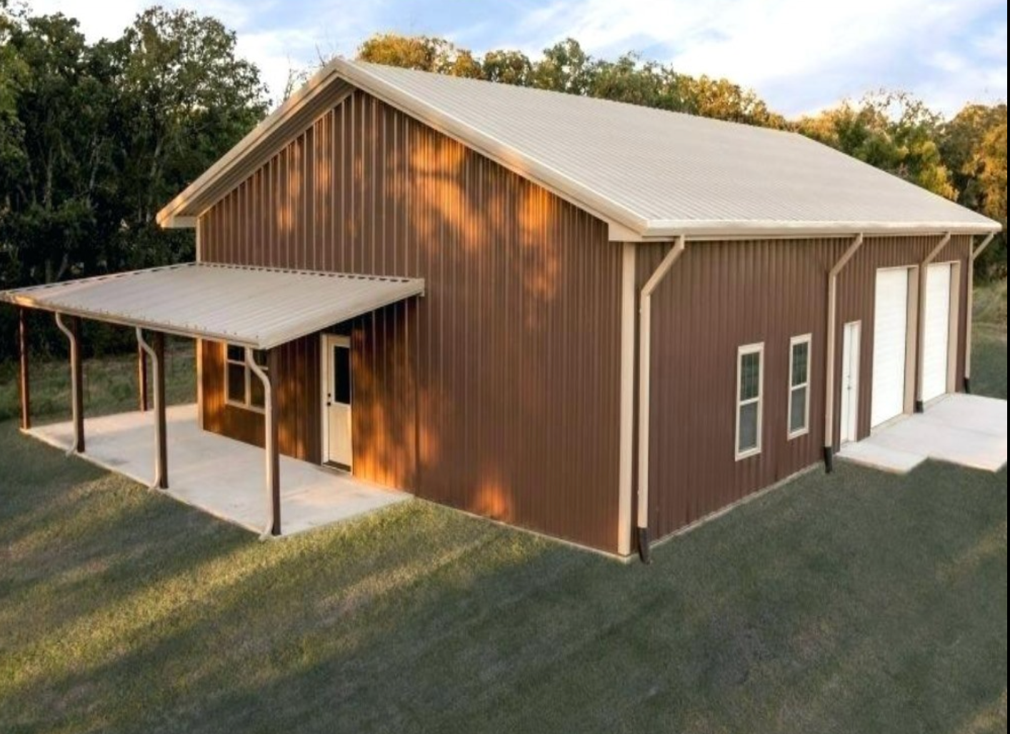 Brown barn-style house with white trim and metal roof, viewed from outside on a grassy lot.