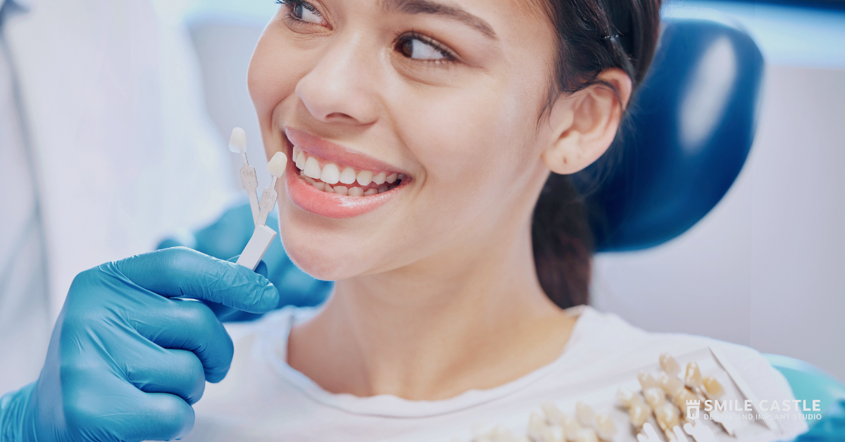 Dentist examining a smiling patient’s teeth with blue gloves in a bright clinic
