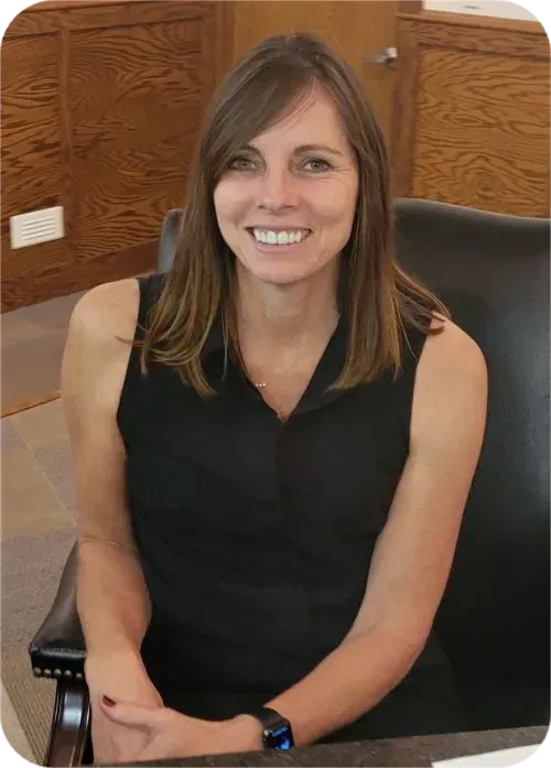 Woman in black sleeveless shirt smiling at a desk.