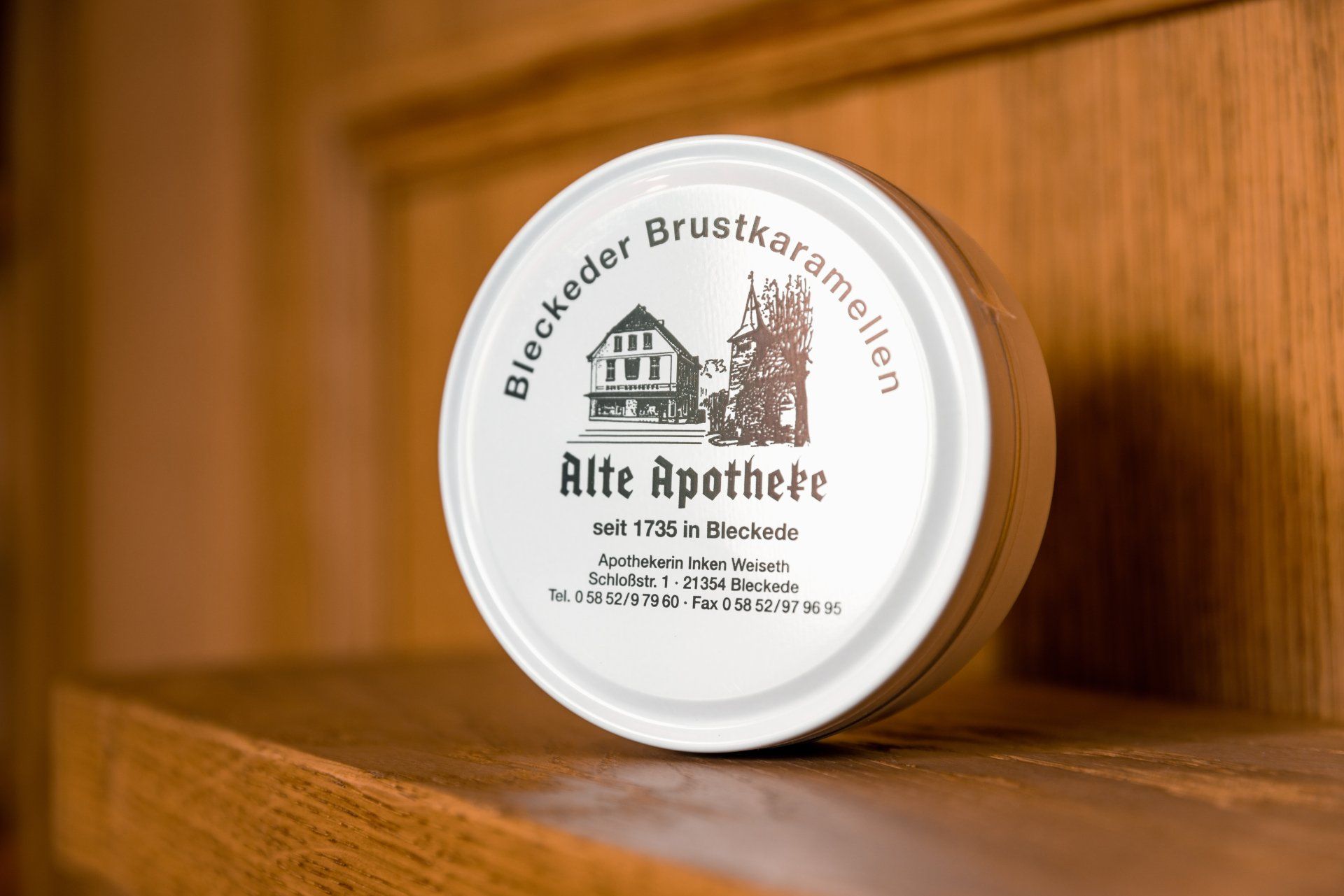 Eine weiße Metalldose mit Bleckeder Brustkaramellen Hustenbonbons der Marke Alte Apotheke steht auf einem Holzregal.