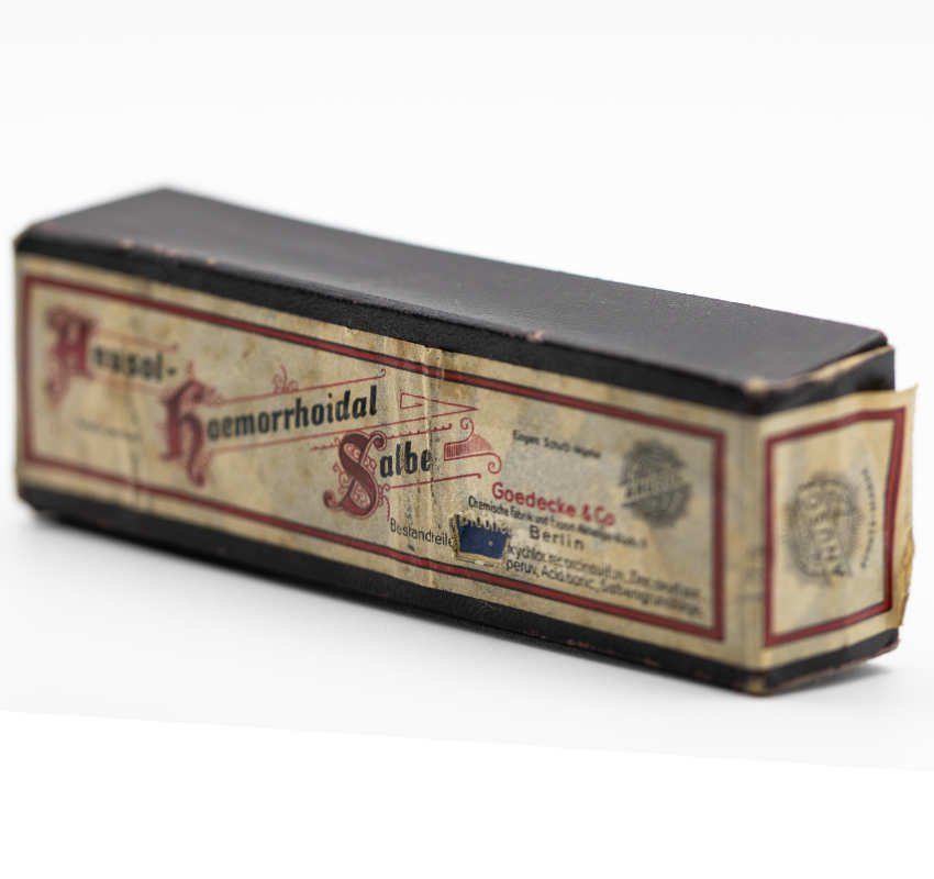 Eine rechteckige Vintage-Schachtel für Heusol-Hämorrhoiden-Salbe von Goedecke & Co., Berlin, in schwarzer und cremefarbener Verpackung.