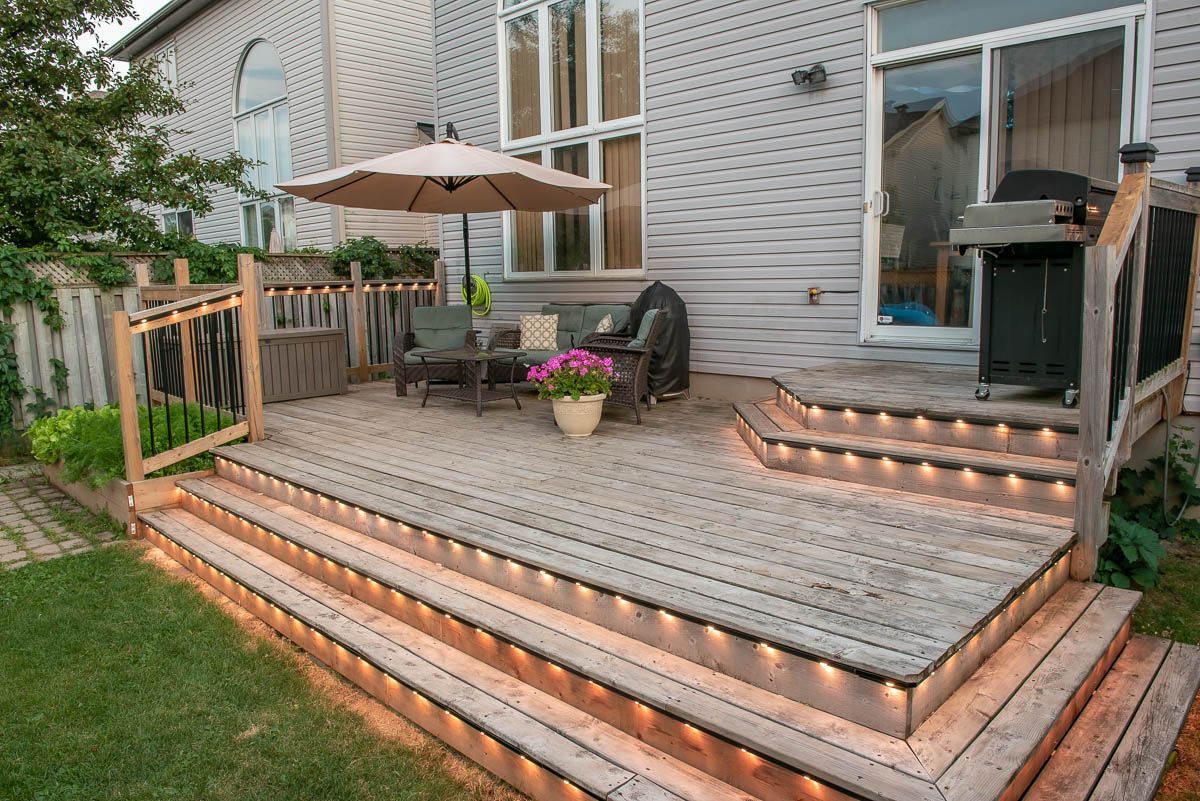 A wooden deck with permanent holiday lighting on stairs and railings | St. Lawrence Luxury Lighting