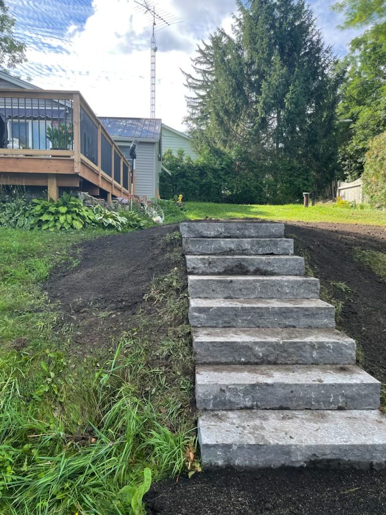 Stone steps lead up a grassy hillside towards a wooden deck and house.