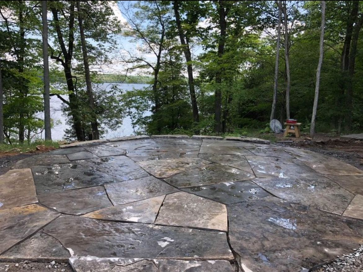 Stone patio overlooking a lake, surrounded by trees.