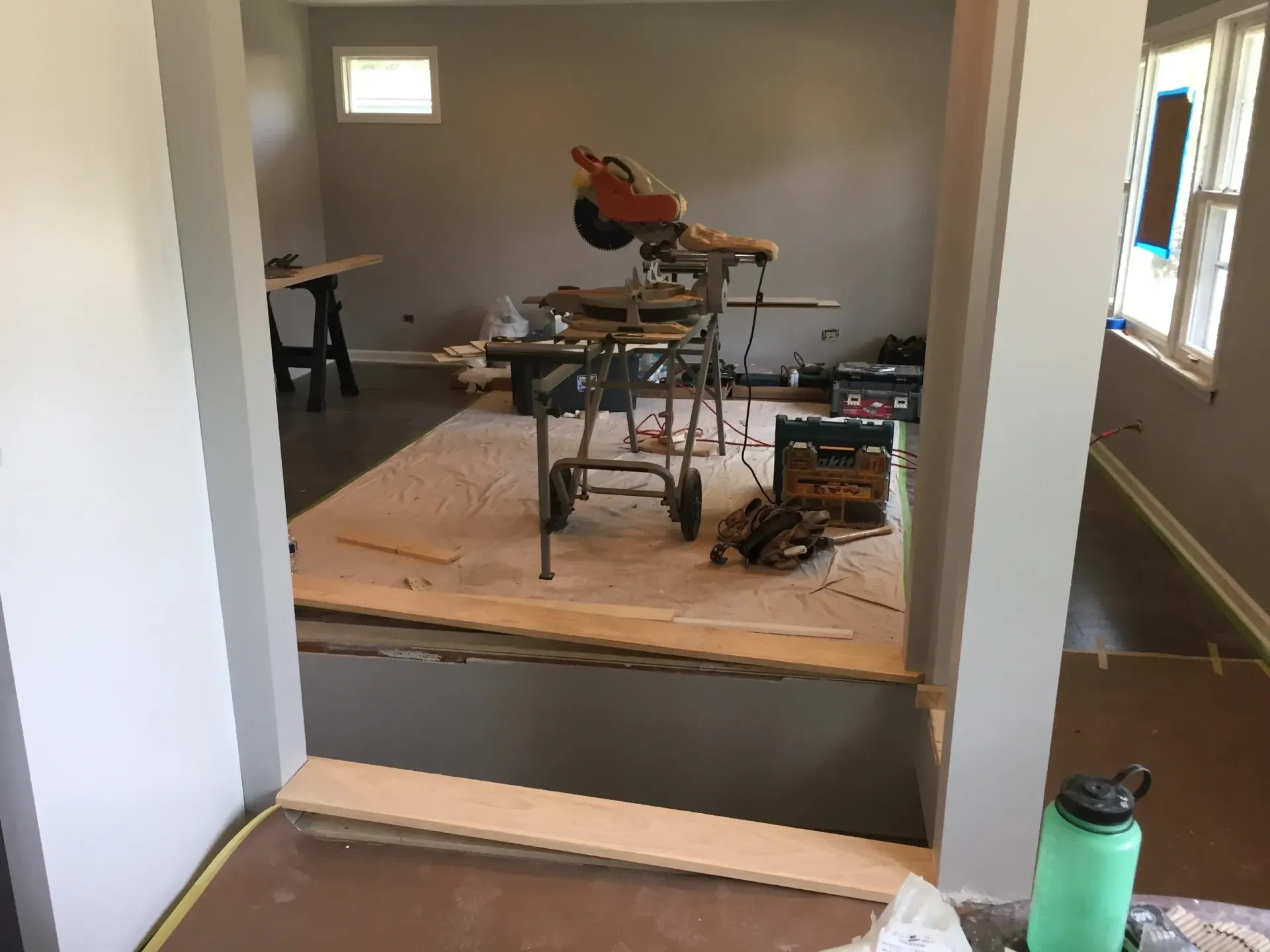 Framed doorway with construction in progress. A miter saw sits on a wheeled stand.