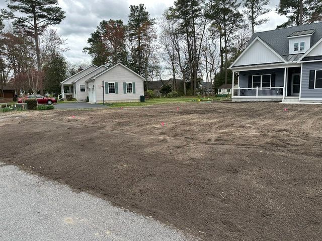 Bare dirt lot between two small houses on an overcast day