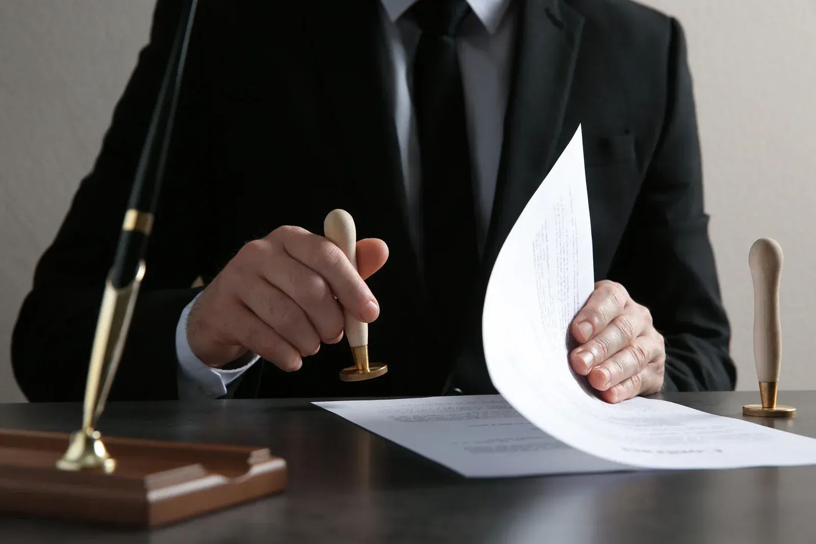 A person in a suit is stamping a document with a wooden stamp in an office setting.