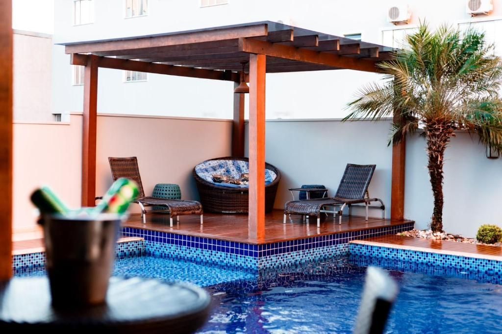 Uma piscina com uma pérgola e cadeiras ao redor