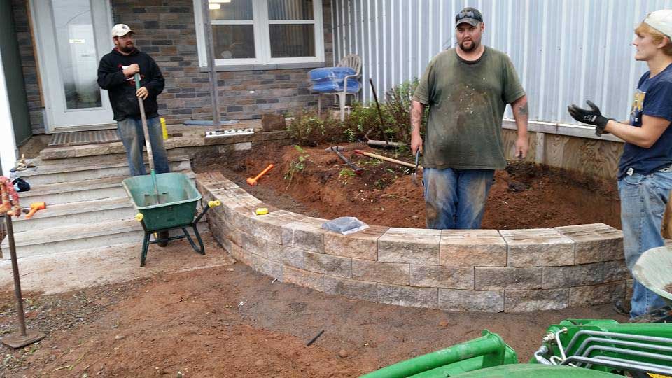 A group of people are working on a patio in front of a house.