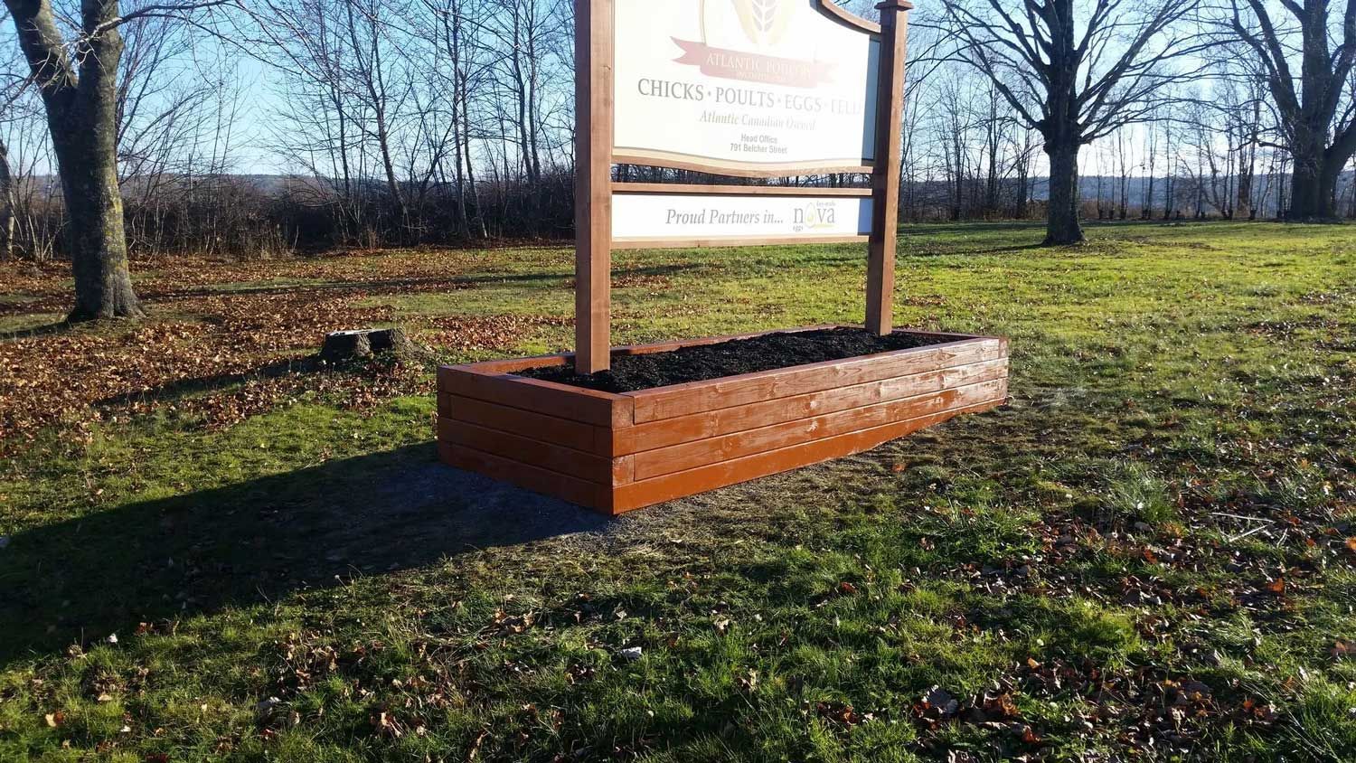 A large wooden sign is sitting in the middle of a grassy field.