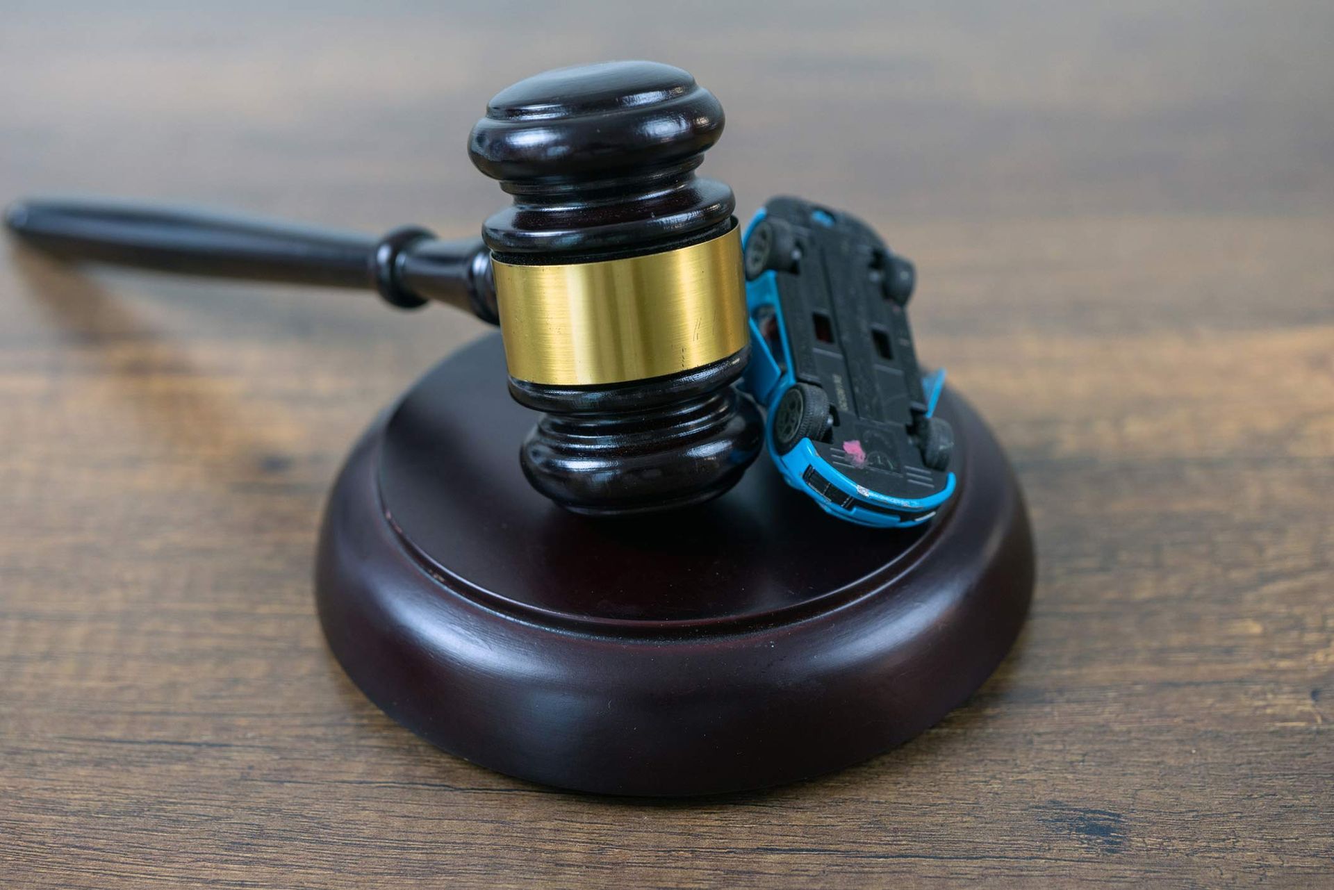 Gavel striking a toy car, symbolizing legal action in an auto accident case.