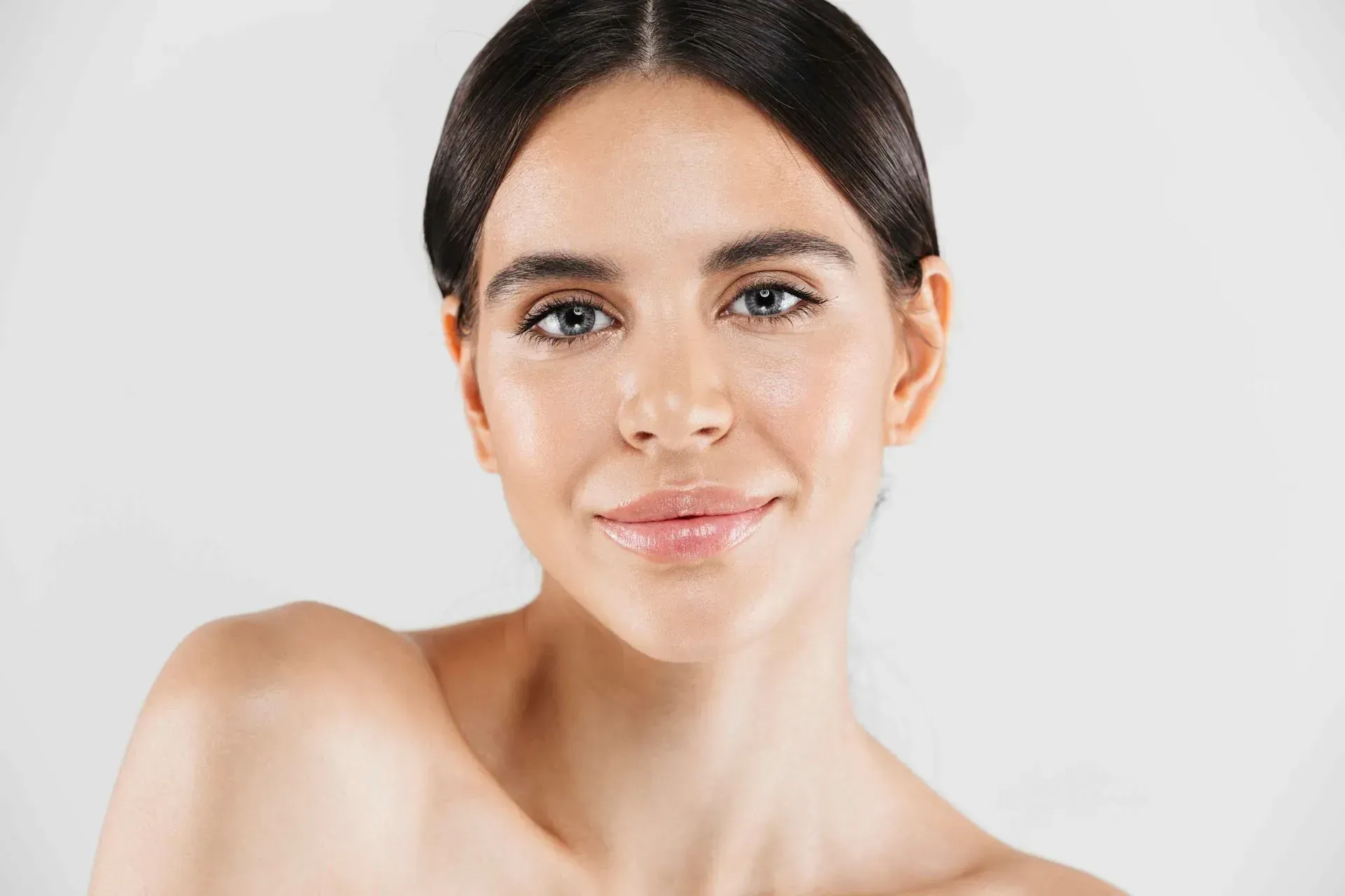 Portrait of a smiling person with dark hair against a light background