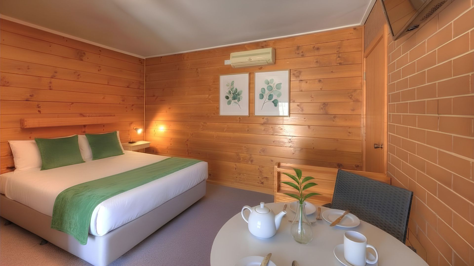 Bedroom with double bed, wood-paneled wall, gray carpet, and white doors.