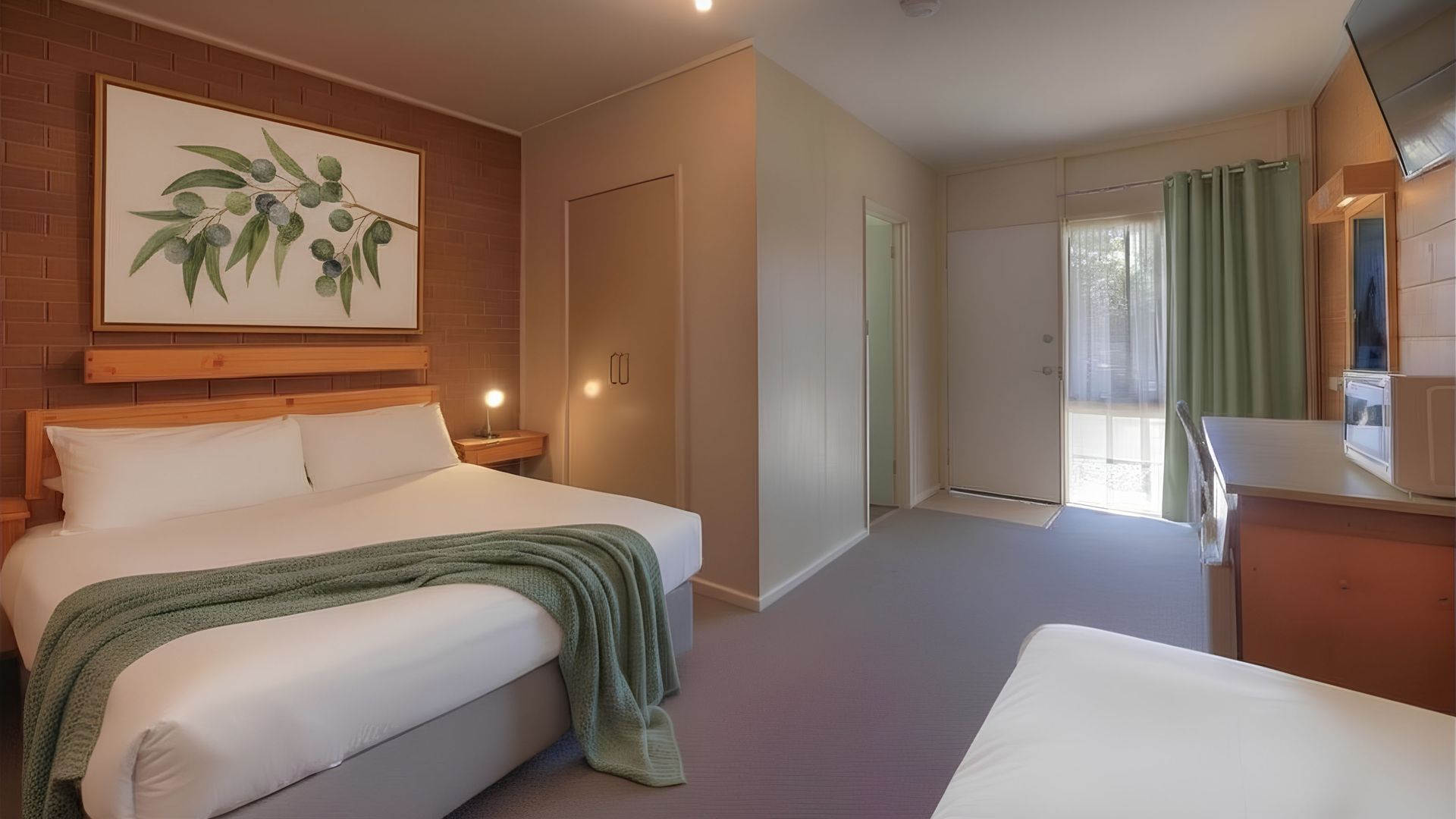 Hotel room with a double bed and a single bed. Wooden walls and brown carpet.
