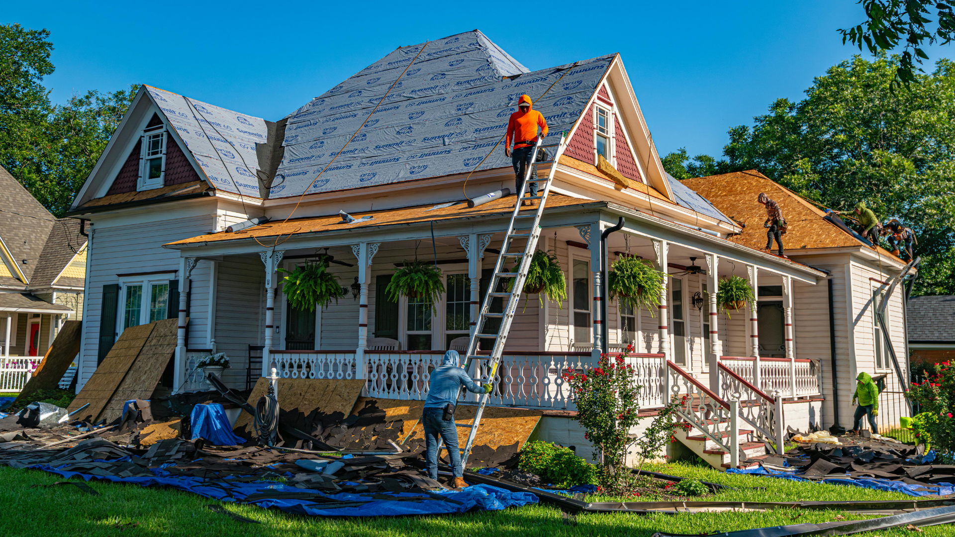 Workers roofing a house with ladders and scaffolding on a sunny day