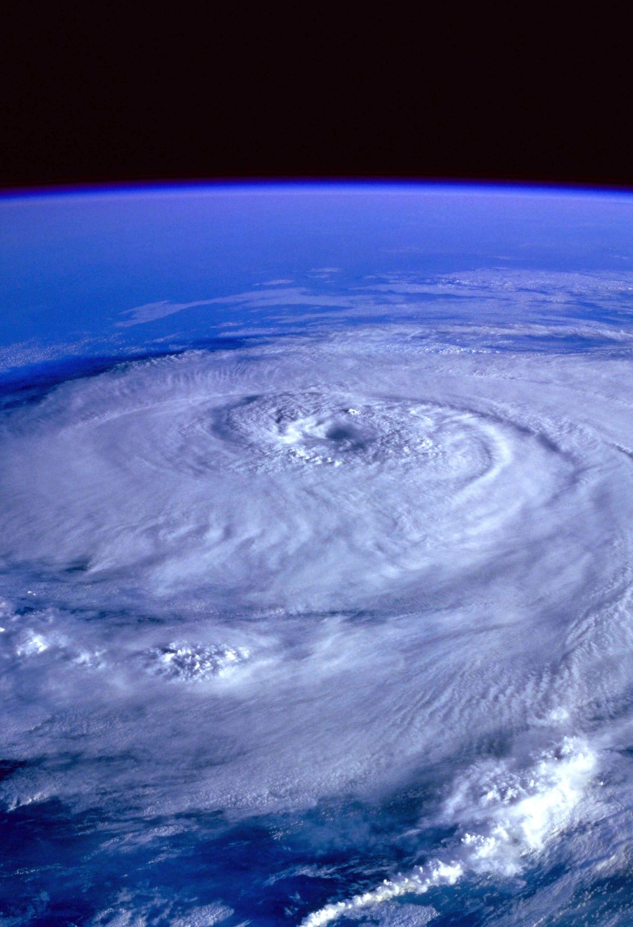 Spiral hurricane over the ocean with a clearly defined eye and blue Earth horizon above it