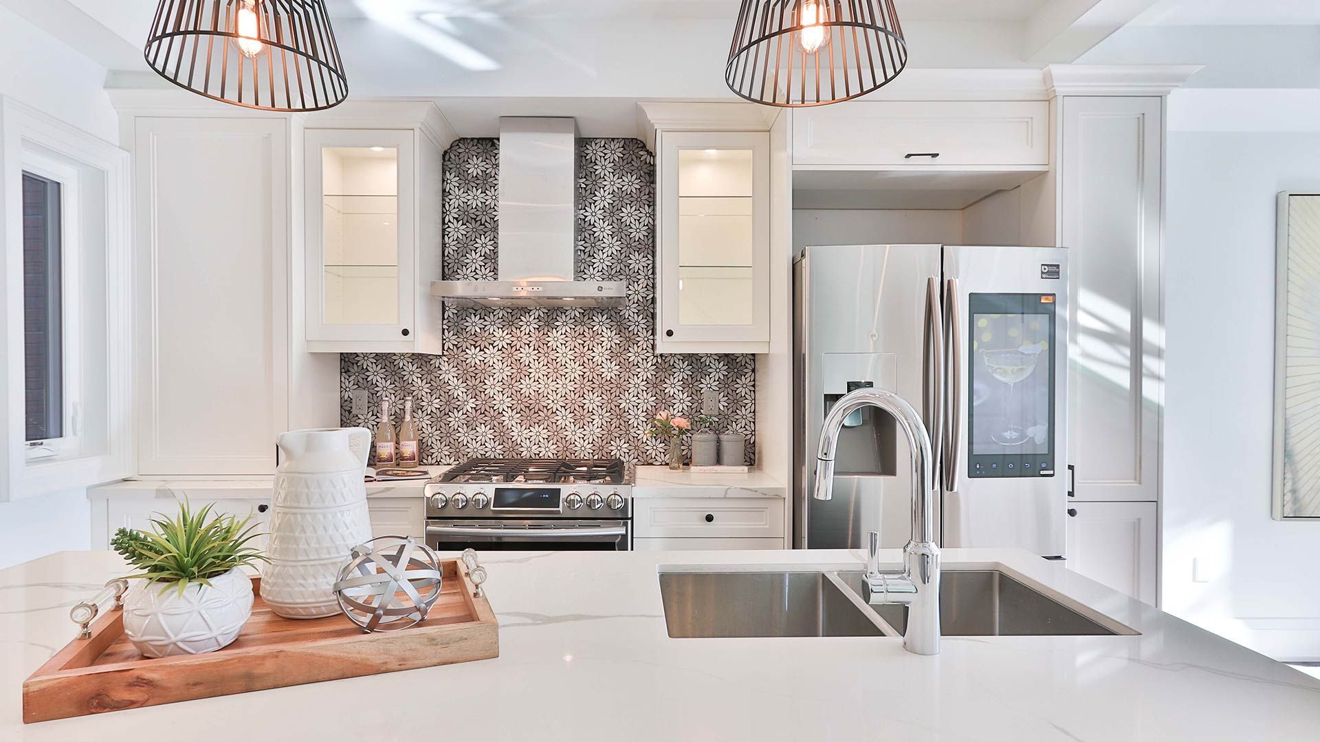 A kitchen with white cabinets , stainless steel appliances , a sink and a refrigerator.