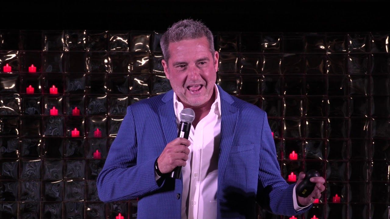 A man in a blue suit is holding a microphone on a stage.
