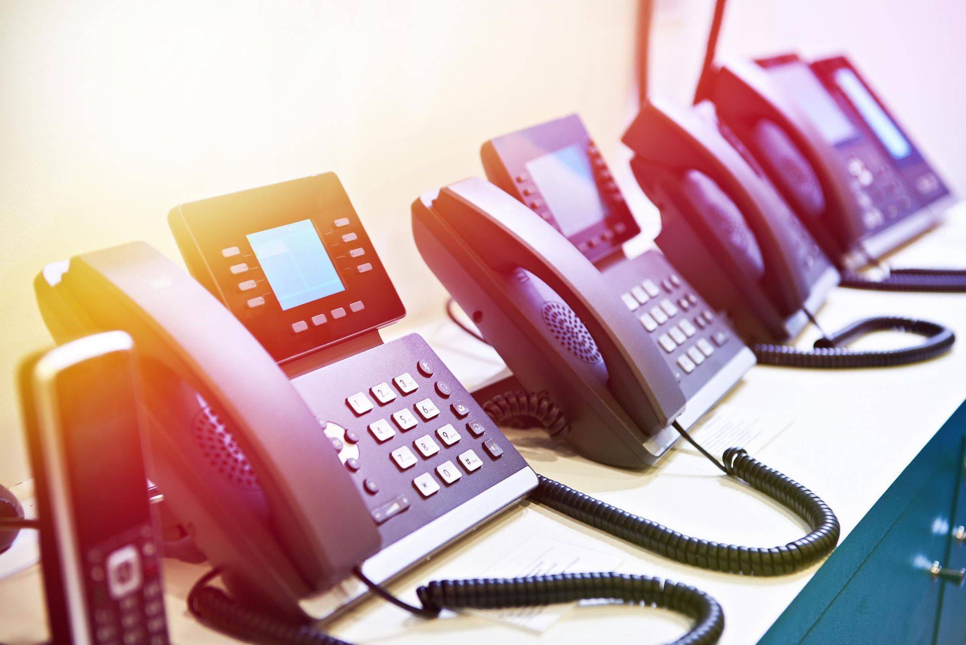 A row of telephones sitting on top of a desk.