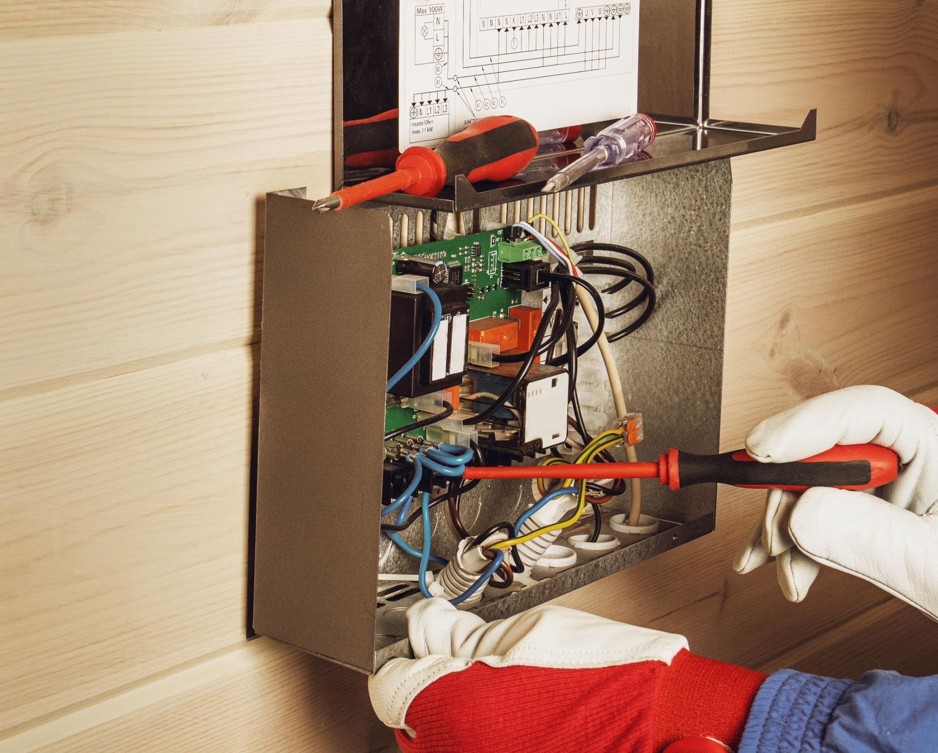 A person is working on an electrical box with a screwdriver.