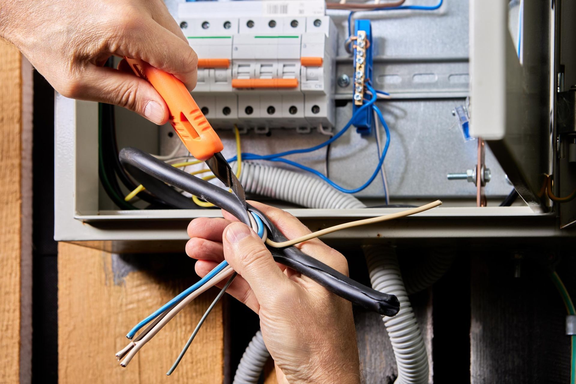 A person is working on an electrical box with a pair of pliers.