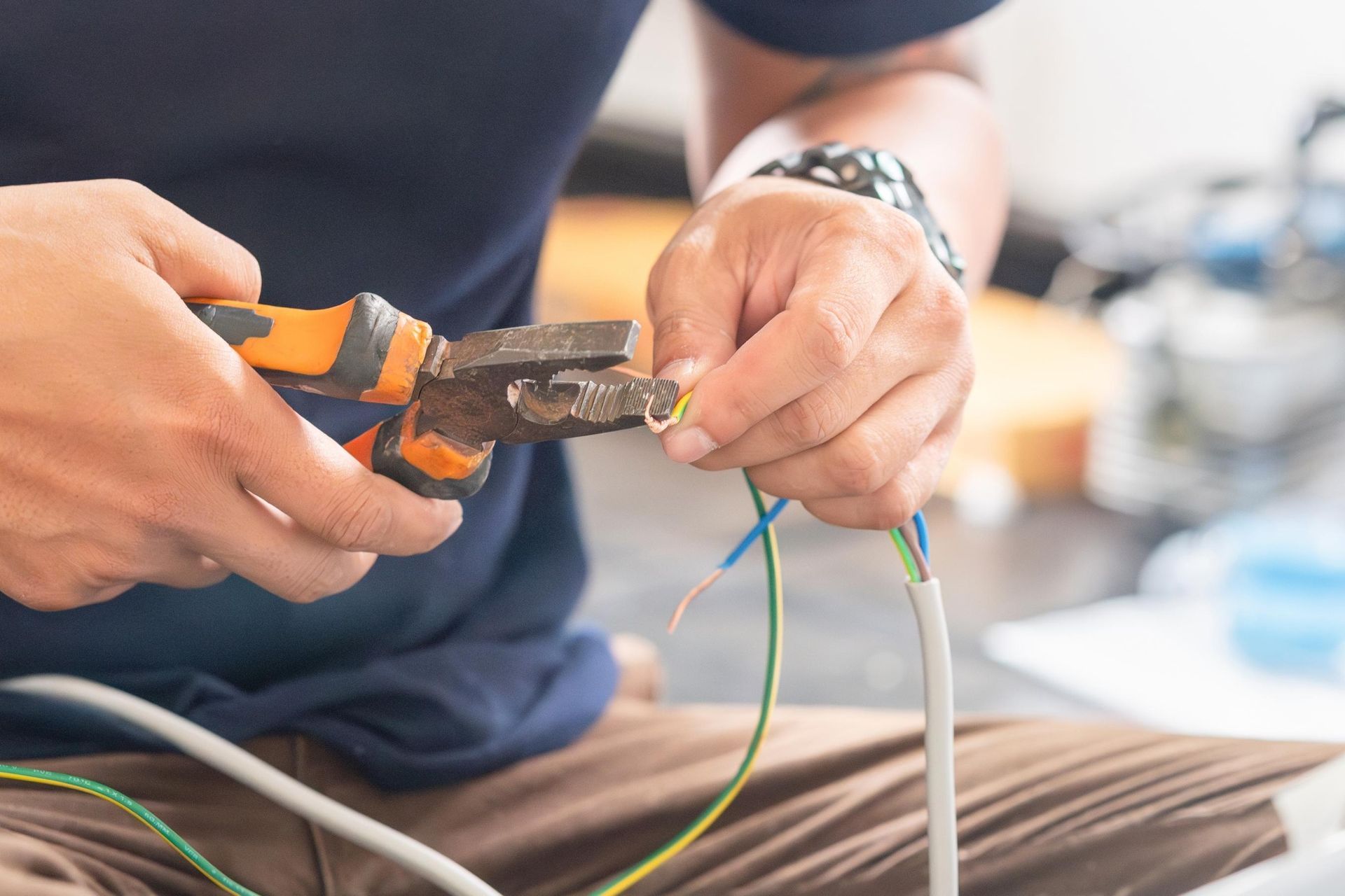 A man is cutting a wire with a pair of pliers.