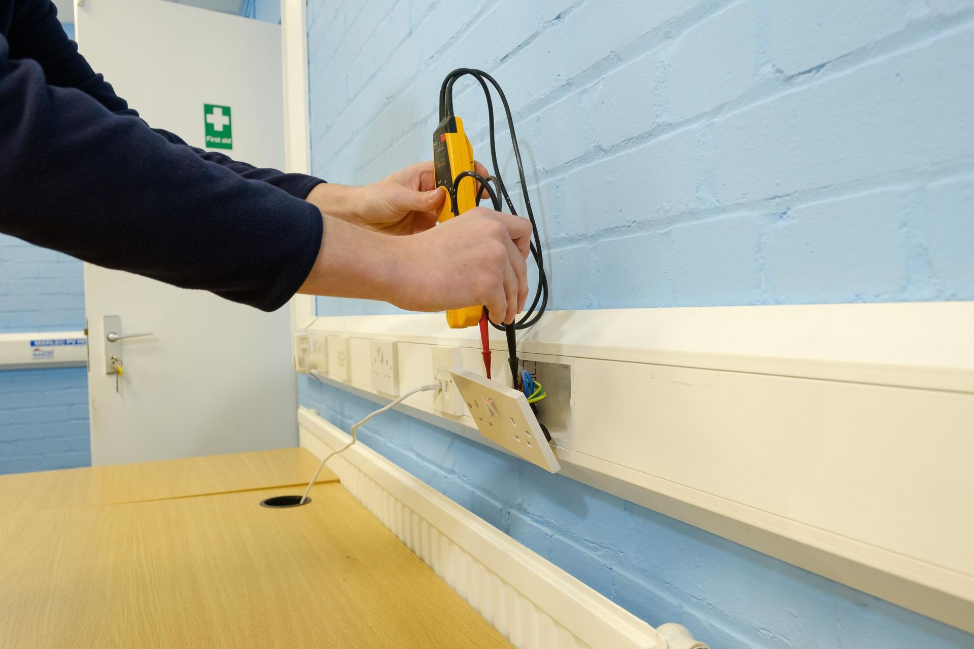 A person is working on a wall with a yellow tool.