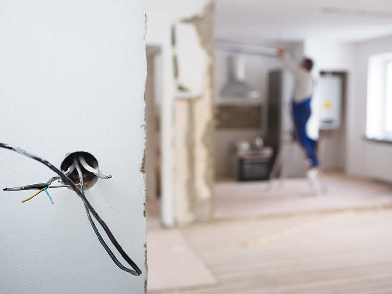 A person is standing in a room with a hole in the wall.