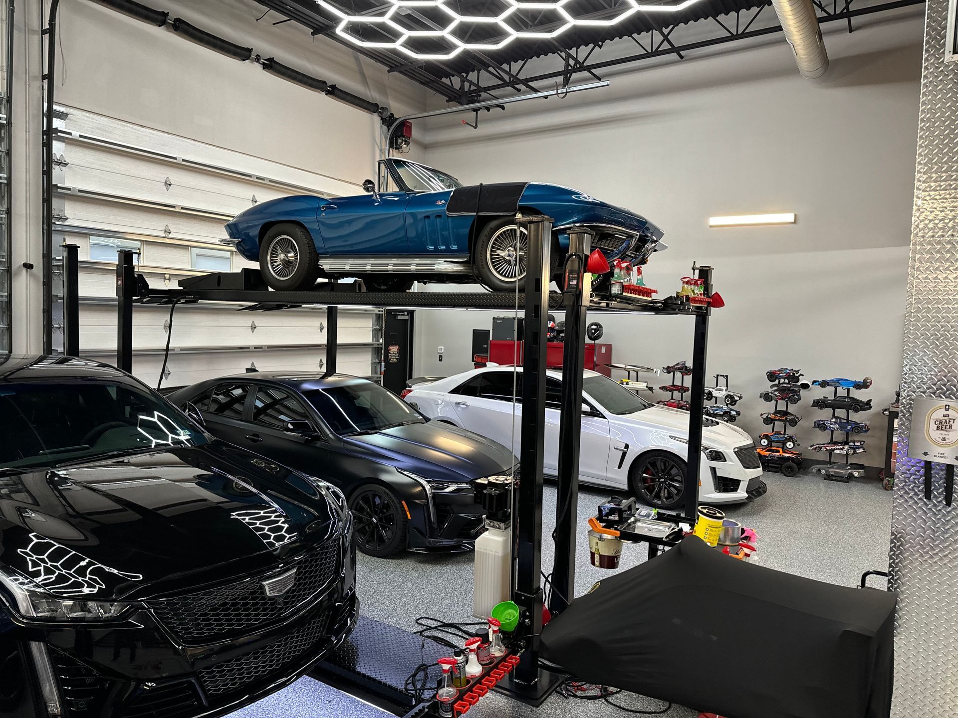 Garage with several cars, including a blue convertible on a lift. | Auto Motive