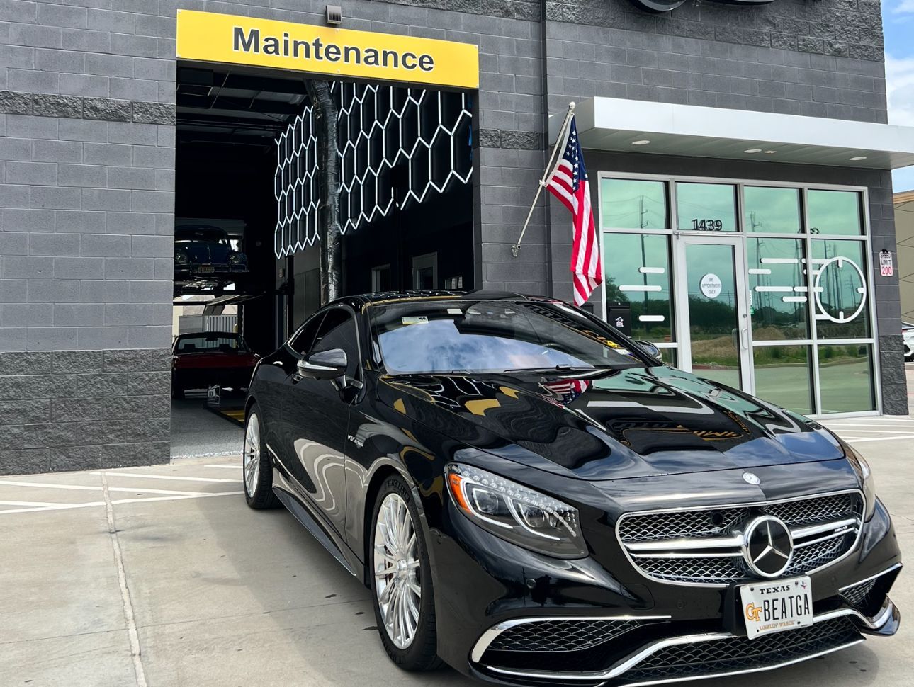 Black Mercedes-Benz parked in front of a garage with a 