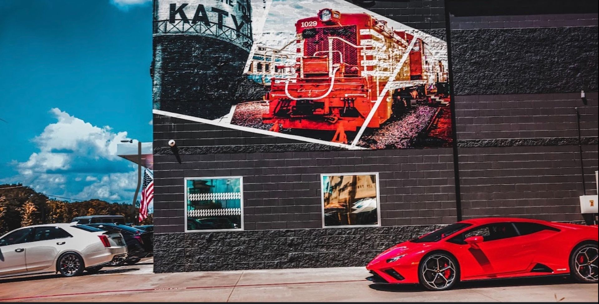 A red sports car in front of a mural of a train with cars. Katy, TX. | Auto Motive
