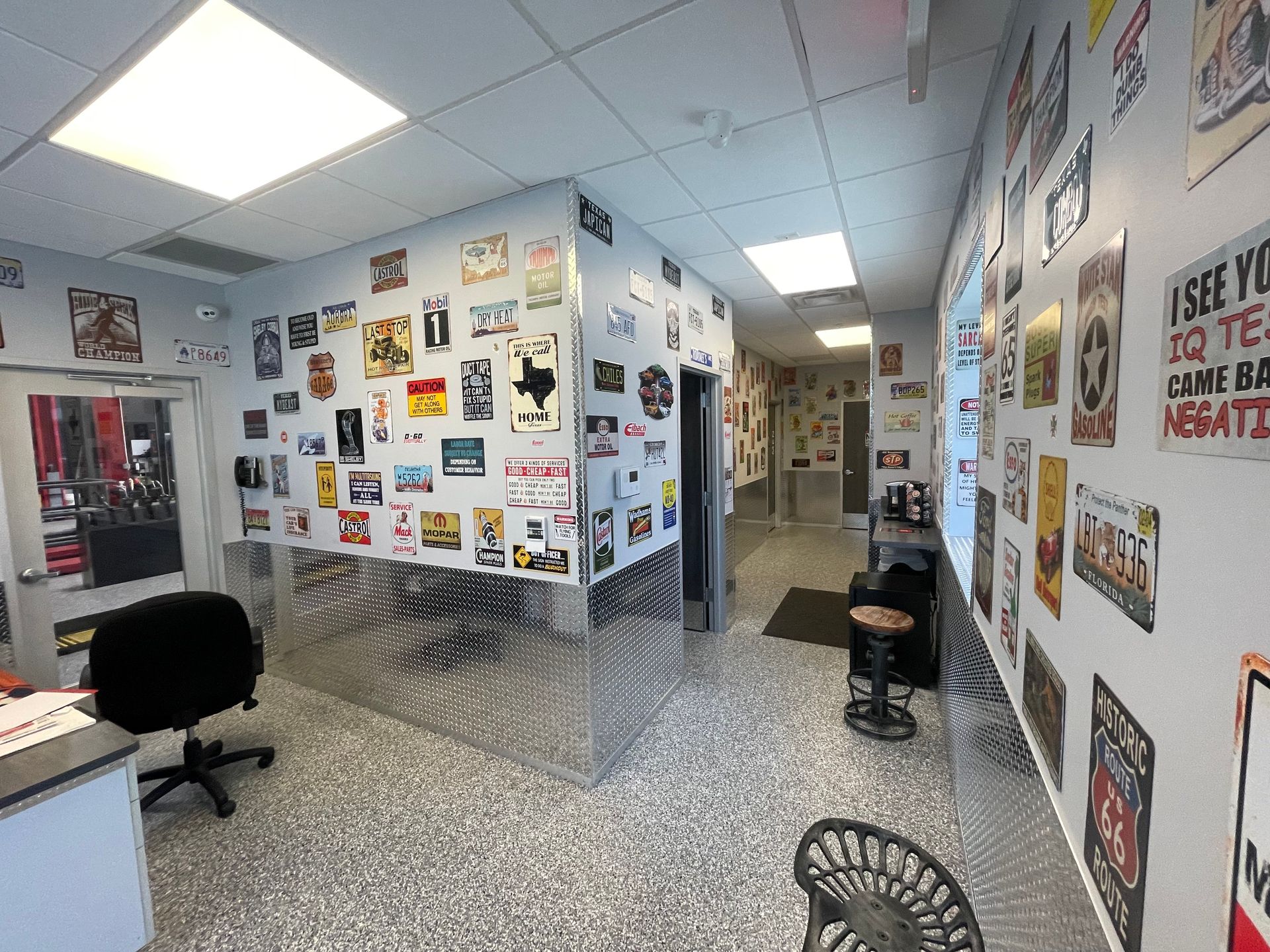 Interior of a business, decorated with signs. A desk, chairs, and a hallway are visible. | Auto Motive