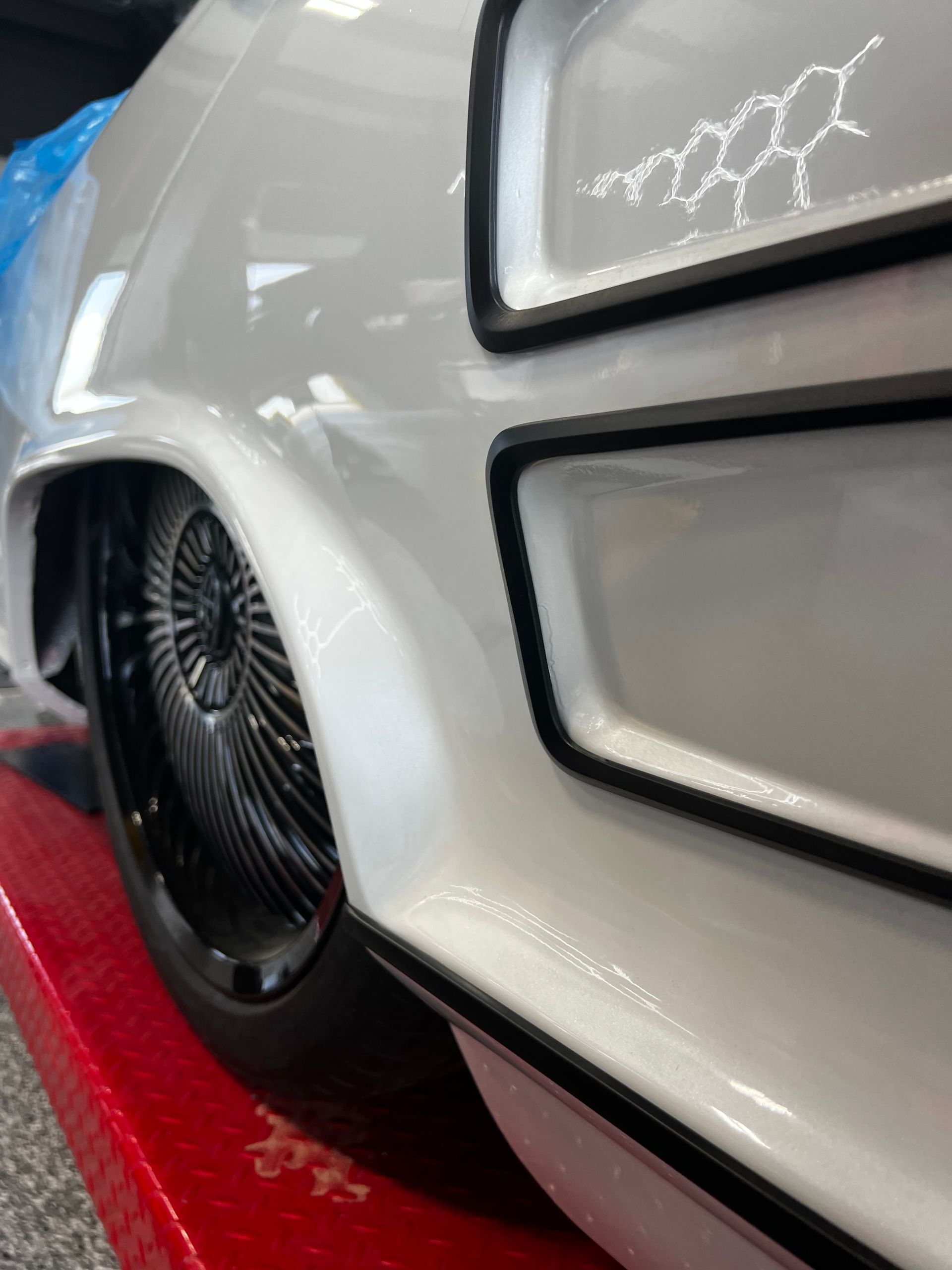 Close-up of a white, custom car's rear quarter panel. Black rim, black trim, and scientific design details. | Auto Motive
