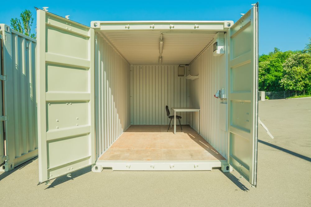 An Empty Shipping Container With Its Doors Open And A Desk — Port Stephens Removals & Storage In Salt Ash, NSW