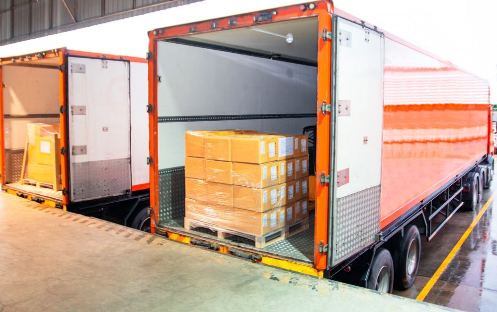 Two Semi Trucks Are Parked Next To Each Other In A Warehouse — Port Stephens Removals & Storage In Salt Ash, NSW