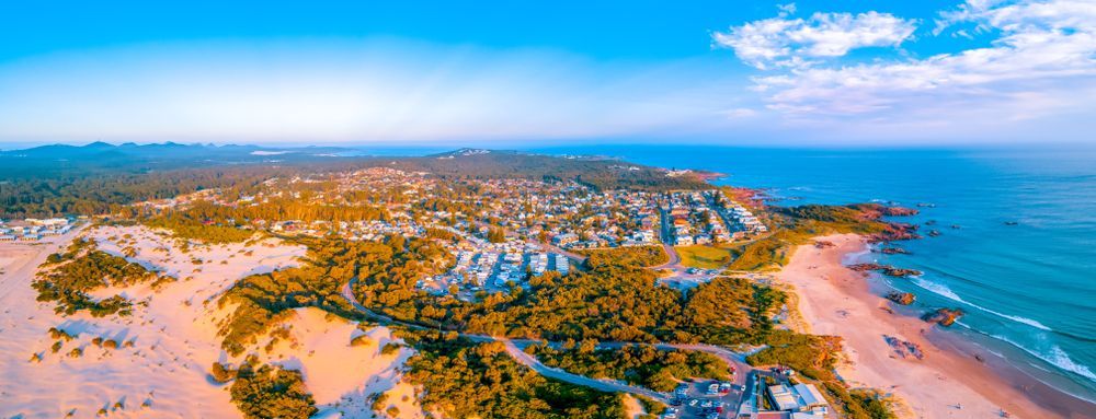 An aerial view of a beach with a city in the distance. — Port Stephens Removals & Storage In Anna Bay, NSW