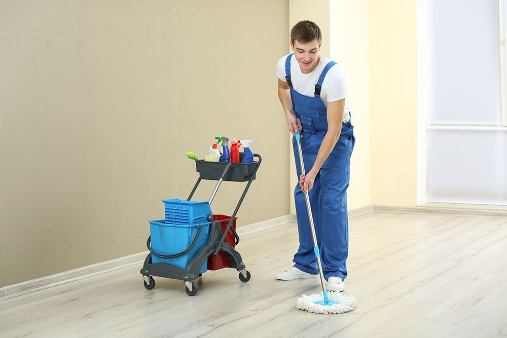 A Man is Cleaning the Floor With a Mop in a Room — Port Stephens Removals & Storage In Salt Ash, NSW