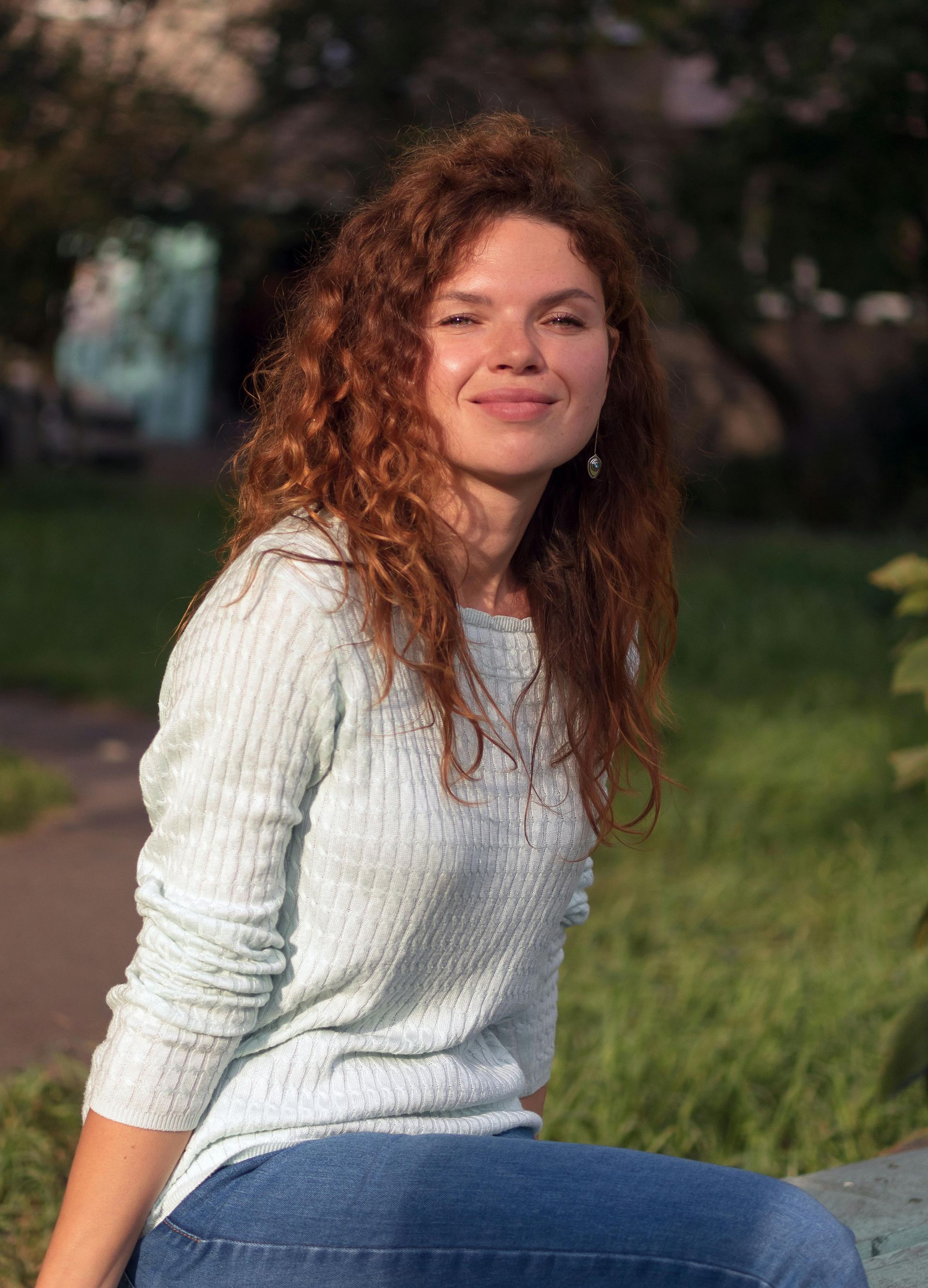 Happy woman sitting on grass outside in a park