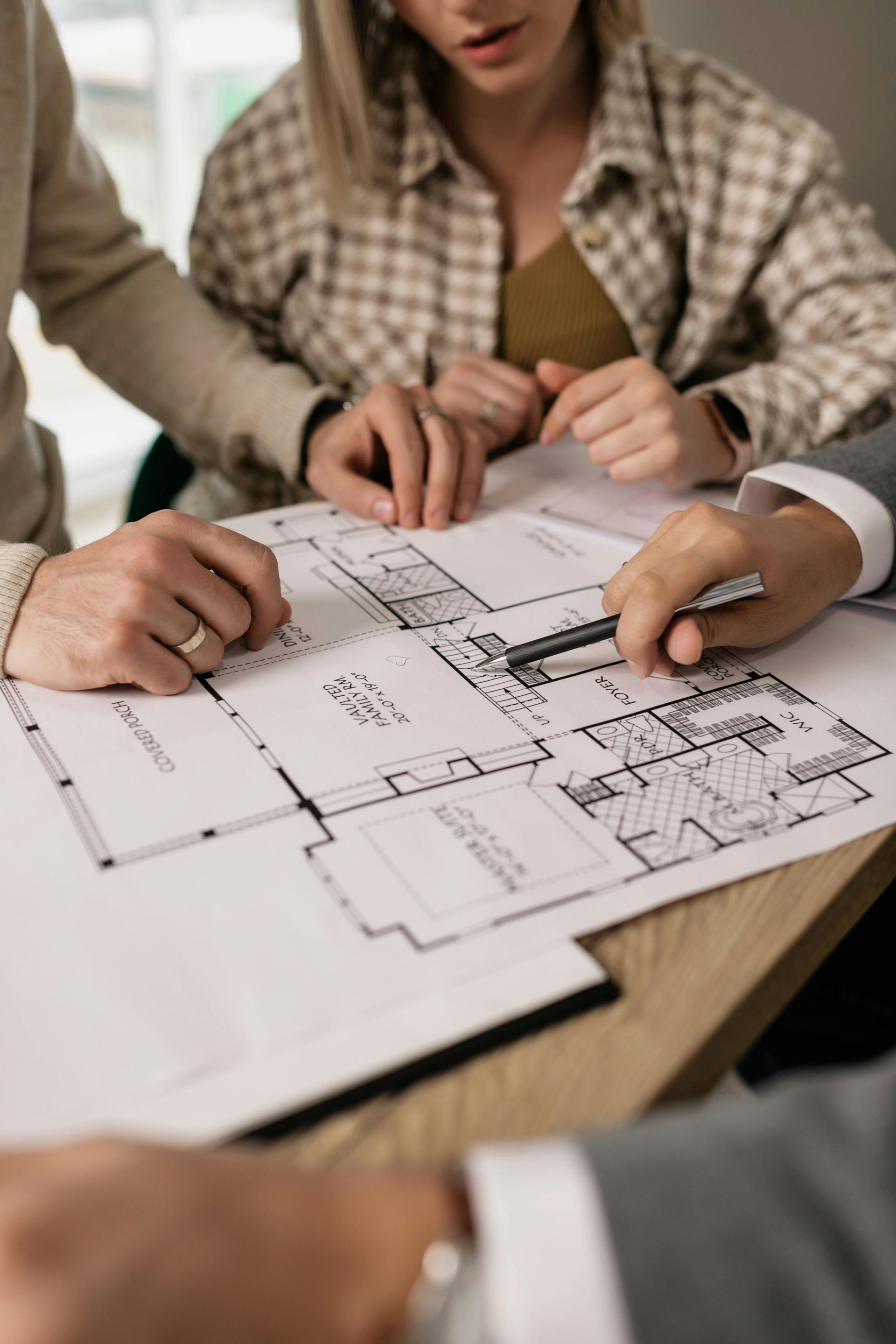 A group of people are sitting around a table looking at a floor plan.