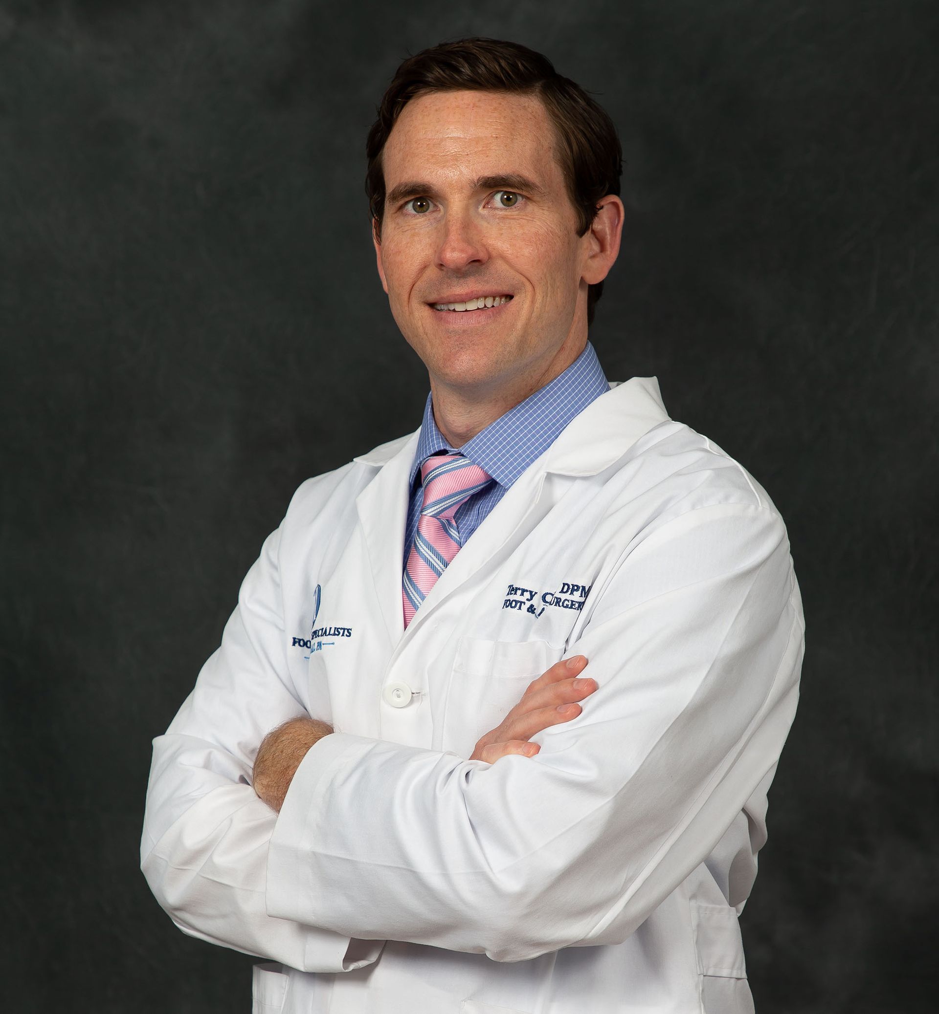 A smiling doctor in a lab coat with a stethoscope around his neck.
