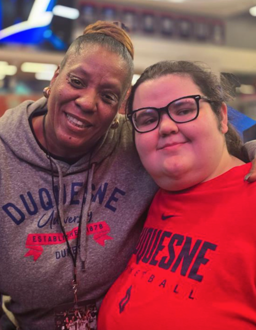 Two people smiling and posing for a photo, both wearing Duquesne University gear.