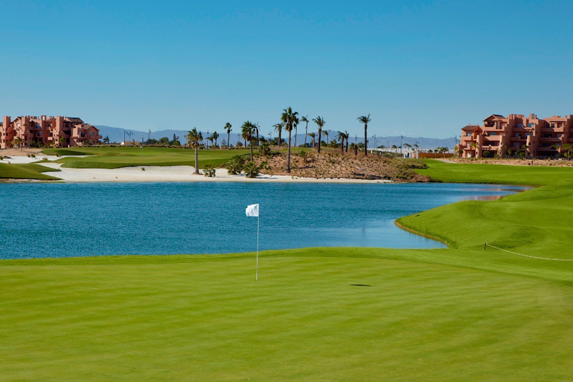 A man is hitting a golf ball out of a bunker on a golf course.