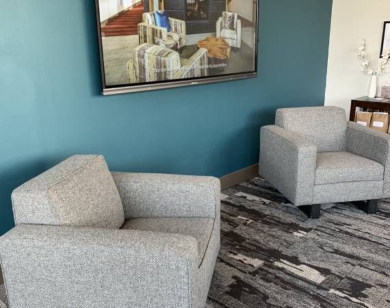 A living room with two chairs and a television on the wall.