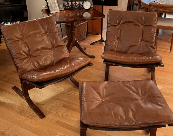 Two brown leather chairs and an ottoman in a living room