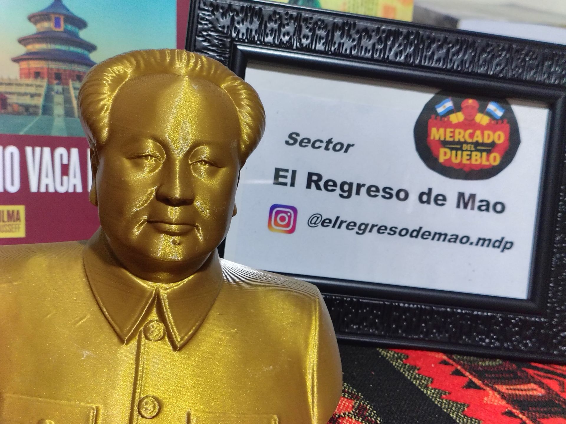 A gold bust of Mao Zedong sits next to a framed sign reading 