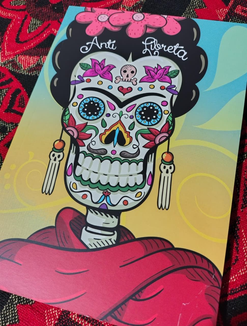 ilustración estilizada de una calavera al estilo de Frida Kahlo, decorada con flores y estampados, en la portada