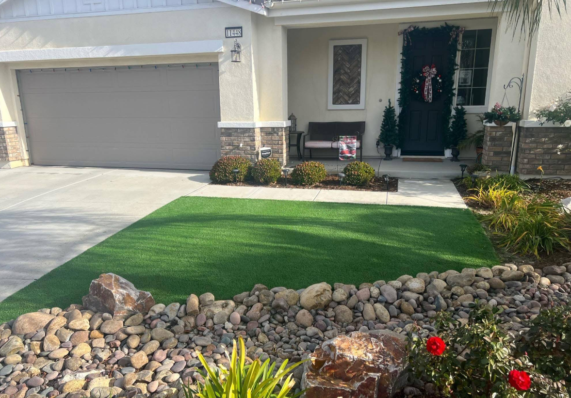 Suburban house front entry with two-car garage, green lawn, and rock landscaping