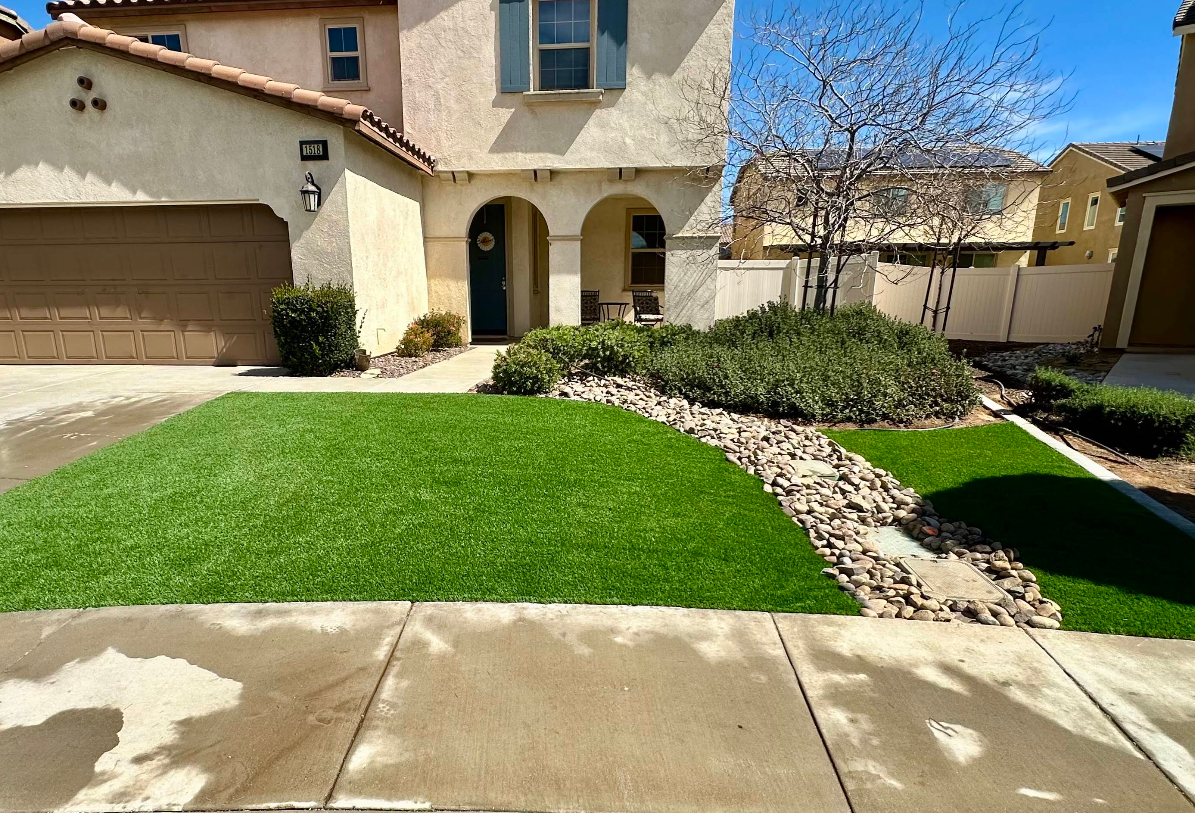 Suburban home with front lawn, curved stone path, and two-car garage under a clear blue sky